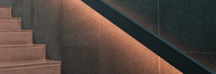 Beleuchtete Steintreppe mit schwarzem Geländer